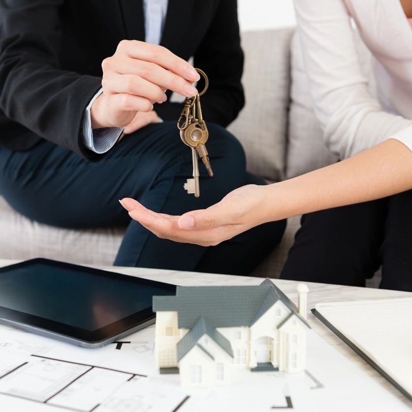 A man and woman are holding keys to their new home.