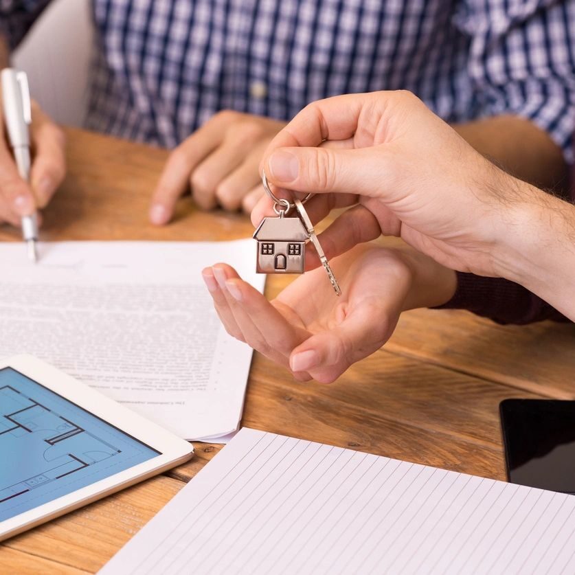 Two people are holding keys to a house.